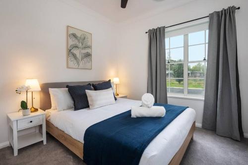 a bedroom with a large bed and a window at McG Mudgee a Hamptons inspired home in Mudgee