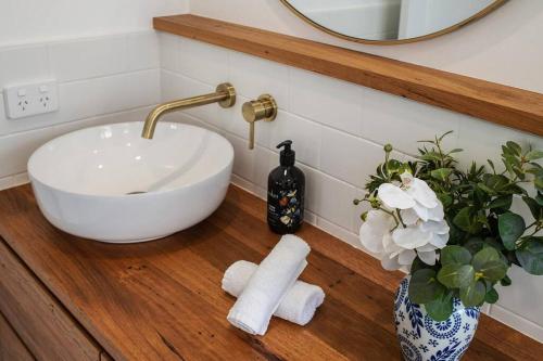 a bathroom with a sink and a vase with towels at McG Mudgee a Hamptons inspired home in Mudgee