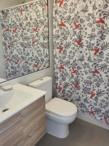 a bathroom with a toilet and a shower curtain with red fishes at Espléndido y cercano a linda playa in Papudo