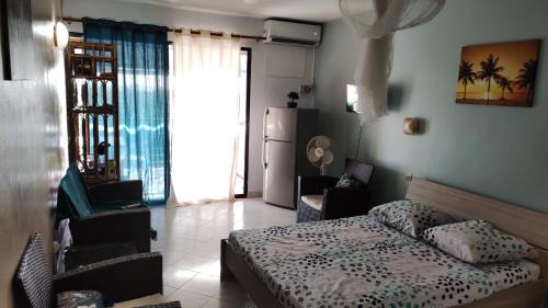 une chambre avec un lit et des chaises dans une pièce dans l'établissement Résidence Frangipaniers, à Sainte-Anne
