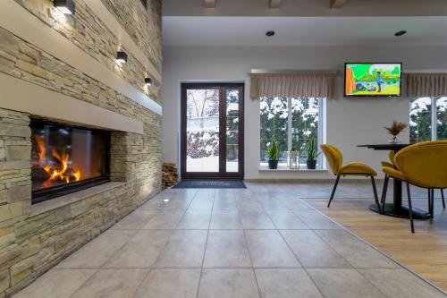 a living room with a fireplace and a table and chairs at Pensjonat Śnieżka SPA in Karpacz