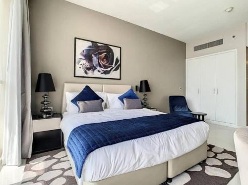 a bedroom with a large bed with blue and white sheets at Brand New Studio in Artesia in Damac Hills in Dubai