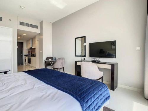 a bedroom with a bed and a desk and a television at Brand New Studio in Artesia in Damac Hills in Dubai