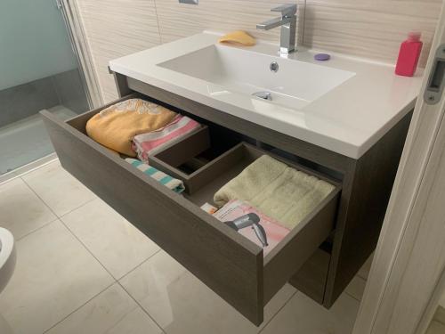 La salle de bains est pourvue d'un lavabo et d'un tiroir avec des serviettes. dans l'établissement Affittacamere EROI, à Feriolo