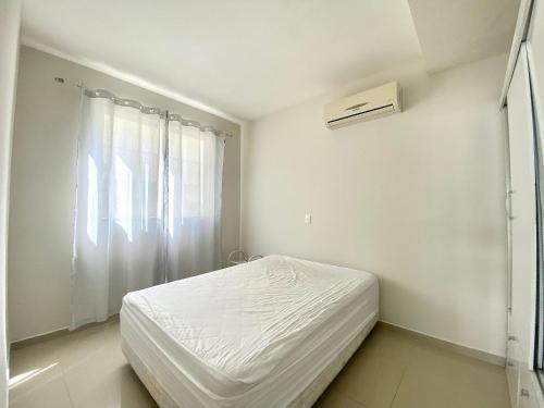 Habitación blanca con cama y ventana en Loft em Bombas - Excelente Localização - 1 dorm 3 pessoas, en Bombinhas