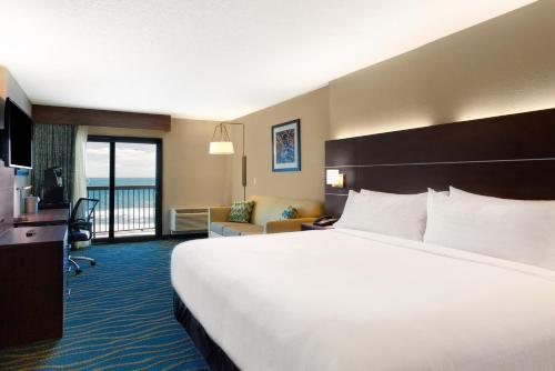 a hotel room with a large bed and a balcony at Holiday Inn Express & Suites Oceanfront Daytona Beach Shores, an IHG Hotel in Daytona Beach