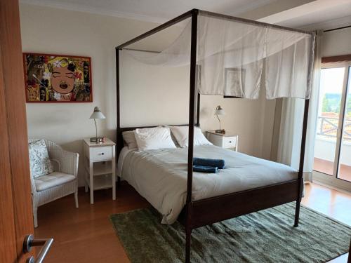 a bedroom with a canopy bed and a chair at GEMA Village in Coimbra