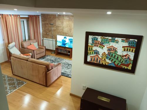 a living room with a couch and a tv at GEMA Village in Coimbra