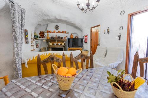 cocina y comedor con mesa y cestas de naranjas en Casa cueva con encanto, en Terque