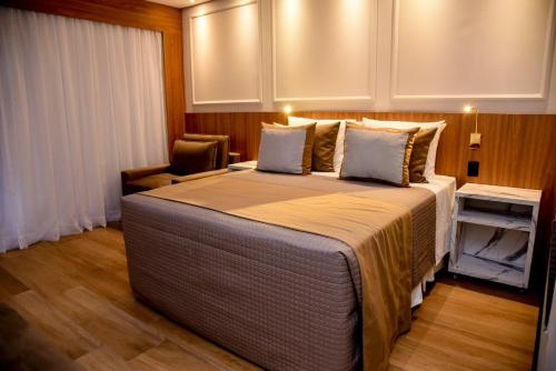 a bedroom with a large bed and a chair at Hotel Titanic Penedo in Penedo