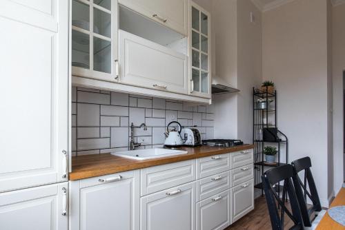 uma cozinha com armários brancos e um lavatório em Olives Marina Apartment Gdańsk em Gdansk