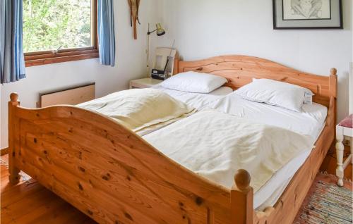 a bedroom with a wooden bed with white sheets at Stunning Home In Magnor With Kitchen in Magnor