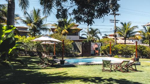 a backyard with a pool and chairs and an umbrella at Bacana Hotel Boutique in Búzios