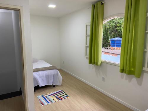 Schlafzimmer mit einem Bett und einem Fenster mit grünen Vorhängen in der Unterkunft A casa azul in Paraty