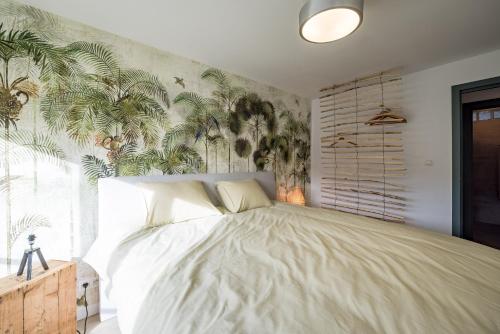 a bedroom with a large bed with a tropical wallpaper at Gîtes in Huy - Appartements chaleureux dans le centre de Huy in Huy