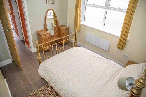 1 dormitorio con cama con espejo y ventana en Chequer - seafront 1 bed ground floor garden flat en Cleethorpes