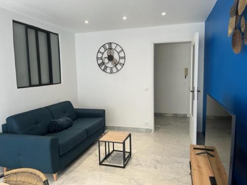 a living room with a blue couch and a clock on the wall at EMPLACEMENT DE PREMIER ORDRE EN BAS DES PLAGES ET DES COMMERCES in Juan-les-Pins