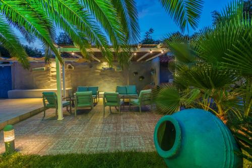 a patio with chairs and a table and palm trees at Hotel Pegasus-Adult Friendly in Limenas