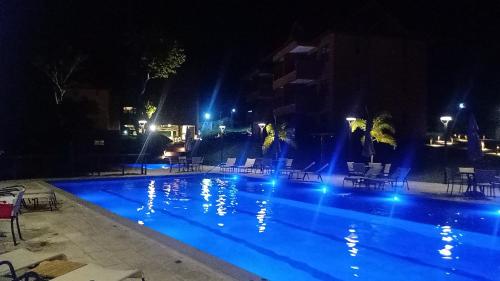 a swimming pool at night with chairs and lights at Vizinho à igrejinha - Apartamento completo no ECO RESORT Praia dos Carneiros in Praia dos Carneiros