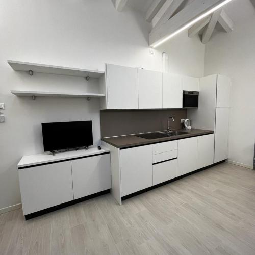 una cocina vacía con armarios blancos y fregadero en Smart Apartments Palazzo Mazzini, en Rovereto
