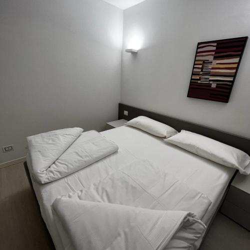 una camera da letto con letto, lenzuola e cuscini bianchi di Smart Apartments Palazzo Mazzini a Rovereto