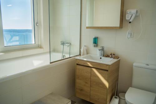 uma casa de banho com um lavatório, um WC e uma janela. em Villa Penelope em Kókkinon Khoríon