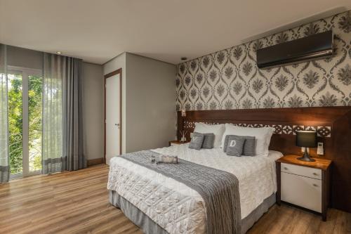 a bedroom with a large bed and a large window at Hotel Valle Dincanto in Gramado