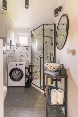 a bathroom with a shower and a washing machine at Ślusarnia-domek z sauną i balią nad jeziorem, Kaszuby in Żuromino