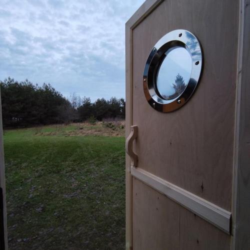 a circle mirror on the side of a wooden door at Ślusarnia-domek z sauną i balią nad jeziorem, Kaszuby in Żuromino