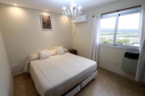 a bedroom with a bed with a chandelier and a window at Departamento JUJUY in San Salvador de Jujuy