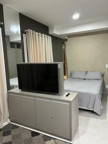a bedroom with a tv on a dresser with a bed at Flat novinho e completo in Sao Jose do Rio Preto