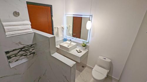 La salle de bains blanche est pourvue d'un lavabo et d'un miroir. dans l'établissement Hotel Fray Select, à Tepic
