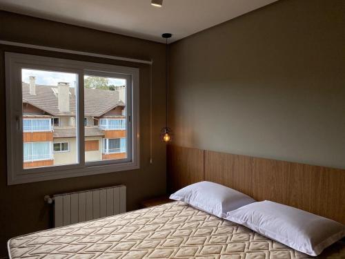 ein Schlafzimmer mit großem Bett und Fenster in der Unterkunft Apartamentos Residencial Villa Rossa by Achei Gramado in Gramado