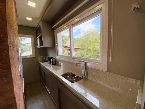 baño con lavabo y ventana en Apartamentos Residencial Villa Rossa by Achei Gramado, en Gramado