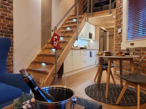a living room with a staircase and a table with a bottle of wine at Wawel Corner Apartment in Kraków