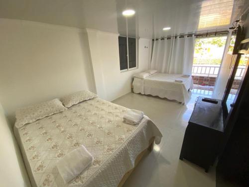 a bedroom with two beds and a large window at Hotel Campestre Dorado SAI in San Andrés