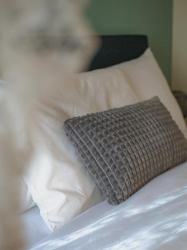 a gray pillow on a bed with white pillows at KP113 All Season Villa in Makrinitsa in Makrinítsa