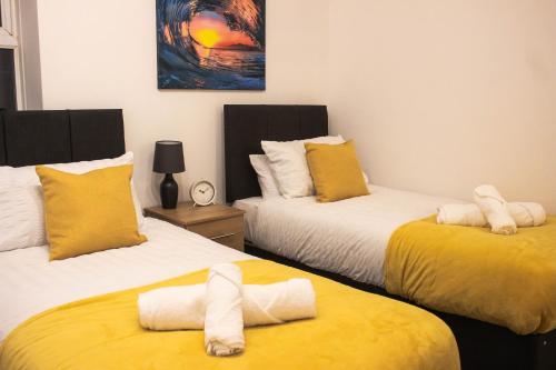 a bedroom with two beds with towels on them at Business friendly 3BR home - King size beds & Centrally located in Swansea