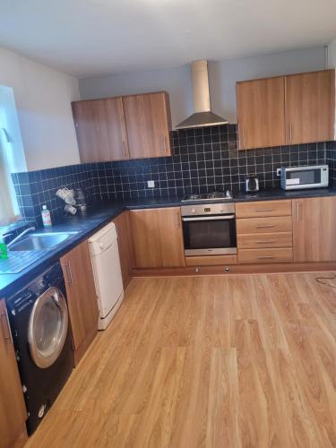 uma cozinha com armários de madeira e uma máquina de lavar e secar roupa em No 2 Decent Home -Large Deluxe bedroom em Dukinfield