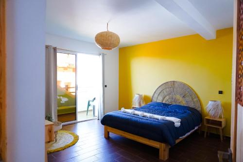 a bedroom with a blue bed and a yellow wall at Dar Mouja, eco-friendly home in Imsouane