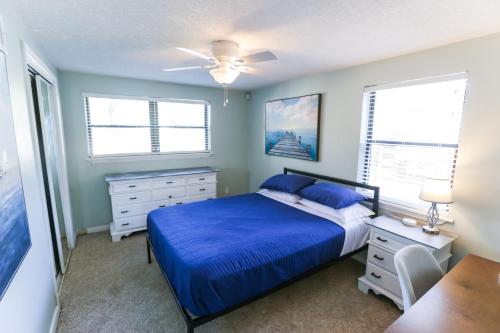 a bedroom with a blue bed and two windows at Pool & Hot Tub Home w Game Room! 1 Mile to Beach! in Jacksonville Beach
