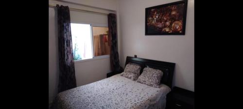 een slaapkamer met een bed met 2 kussens en een raam bij Appartement meublé près du grand souk Elhad in Agadir