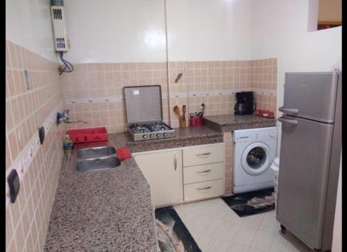 a small kitchen with a sink and a refrigerator at Appartement meublé près du grand souk Elhad in Agadir