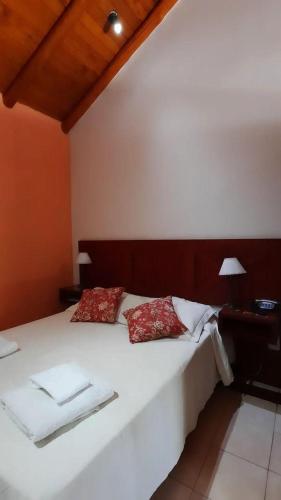 a bedroom with a large white bed with red pillows at Hotel Los Pinares in San Pedro