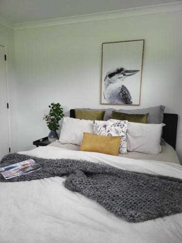 a bedroom with a large white bed with pillows at Kotuku Cottage in Tauranga