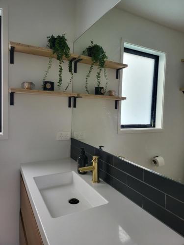 a bathroom with a white sink and a mirror at Kotuku Cottage in Tauranga