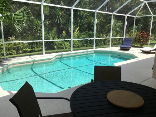 a swimming pool with a table and chairs in front of a building at Family Villa with Private Pool near Disney Parks in Kissimmee