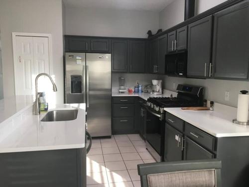 a kitchen with black cabinets and a stainless steel refrigerator at Family Villa with Private Pool near Disney Parks in Kissimmee