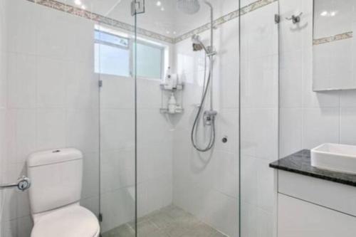 a bathroom with a shower and a toilet and a sink at Bahia by the Beach in Avoca Beach