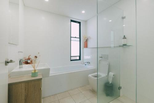 a bathroom with a toilet and a glass shower at ‘The Lumos’ Designer home Close to Olympic Park in Sydney